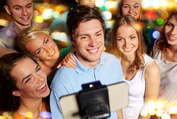 Obraz na płótnie Canvas friends with smartphone taking selfie in club