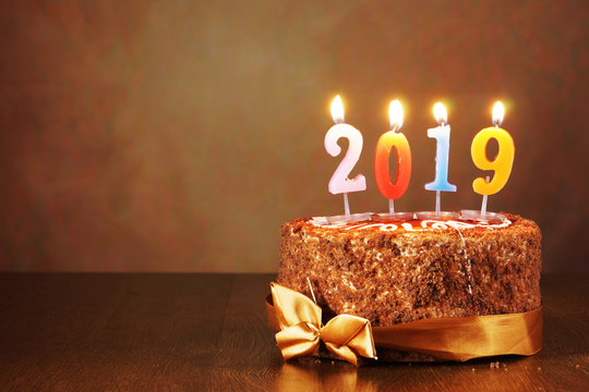 New Year 2019 still life. Chocolate cake and burning candles on brown background