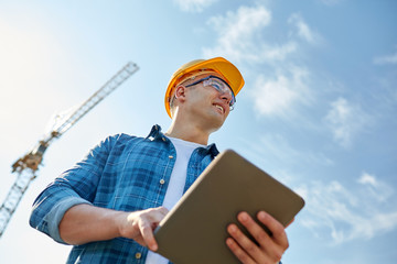 builder in hardhat with tablet pc at construction