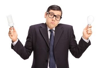 Confused businessman holding two light bulbs