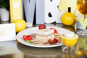 tiramisu with strawberries on a plate lemon letter serving table