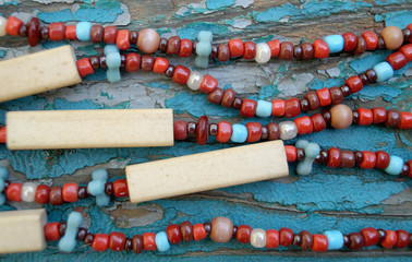 Close up of ethnic colorful beaded necklace on a grunge blue wooden background.