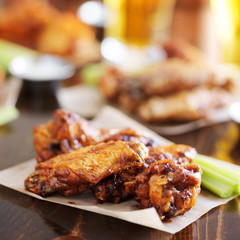 pile of barbecue buffalo chicken wings on wax paper served with celery