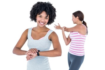 Fototapeta na wymiar Woman wearing wristwatch while female friend exercising