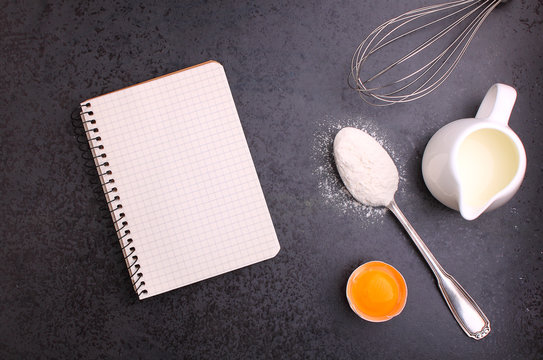 Baking ingredients, flour, egg, milk, and whisk. notebook