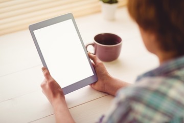  Hands holding digital tablet by coffee cup on table