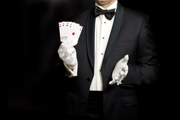 Elegant man in tuxedo holding 4 aces in hand