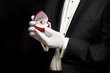 Elegant man in tuxedo holding engagement ring