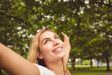 Naklejka premium Cheerful woman with arms raised in park