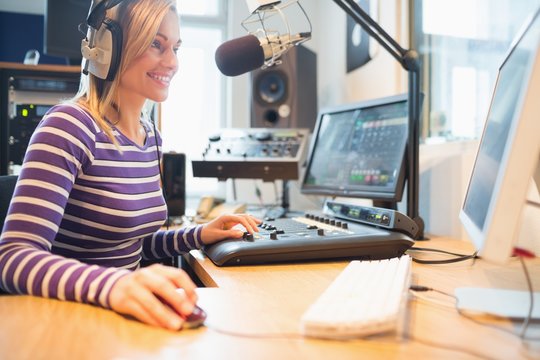 Female radio host using computer while broadcasting