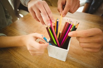 Close-up of cropped hands taking color pencils 