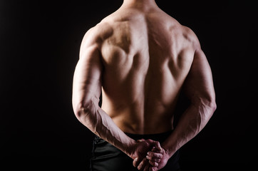 Fototapeta na wymiar Muscular man posing in dark studio
