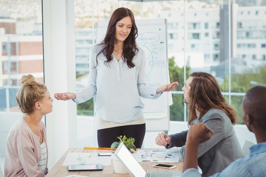 Woman gesturing while discussing with coworkers 