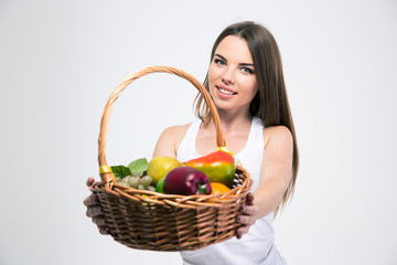 Fototapeta premium Girl giving basket with fruits at the camera