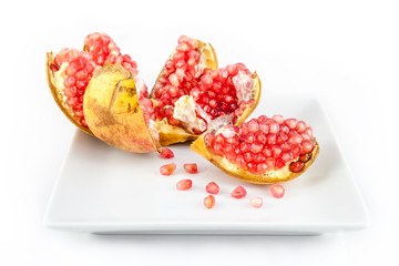 Opened ripe Pomegranate fruit in a plate. Punica granatum peeled to reveal clusters of fresh, juicy and gem-like seeds.