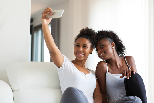 African American teenage girls taking a selfie picture with a sm