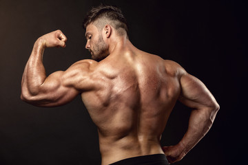 Fototapeta na wymiar Strong Athletic Man Fitness Model posing back muscles, triceps,