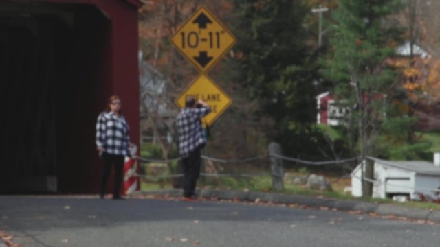 Couple in matching plaid taking pics of covered bridge