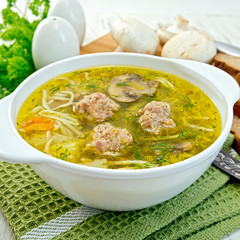 Soup with meatballs and noodles in bowl on napkin