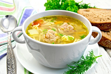 Soup with meatballs and noodles in bowl on saucer