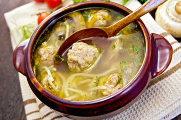 Soup with meatballs and noodles in pottery on napkin
