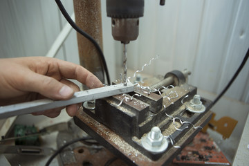 Man drilling in Steel Plate with Bench Drill. Close-up Electric