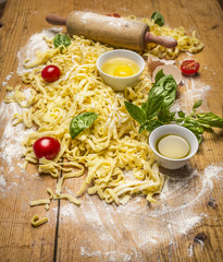 Ingredients for cooking pasta with tomato sauce, eggs ,rolling pin,flour ,olive oil, tomatoes, herbs on on rustic wooden background top view