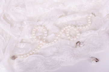 Pearl necklace and earrings on white lace cloth 