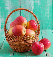 Ripe red apples in a basket on a bright wooden background