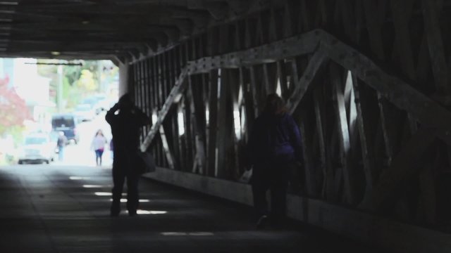 Cars and pedestrians entering covered bridge