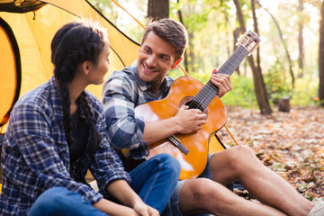 Couple sitting with guitar in the forest