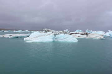 Blaue Eisberge auf Gletschersee J&ouml;kulsarlon, dar&uuml;ber grauer Himmel