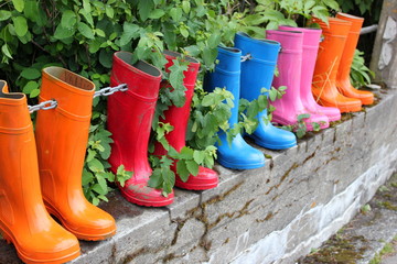 Ein Zaun mit bunten Gummistiefeln als Zaunlatten auf Island