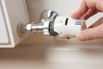 Close Up Of Hand Adjusting Radiator Thermostat