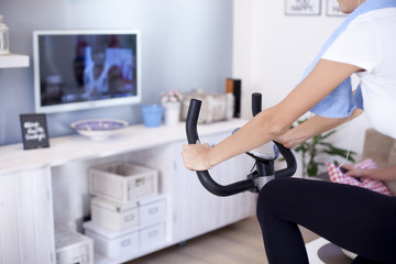 Sporty woman training on exercise bike in the living room,close up