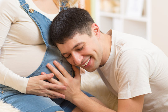 Happy man listening to belly of  his pregnant wife