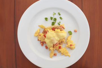 Scrambled egg with cheese and pancake in white dish on wooden table