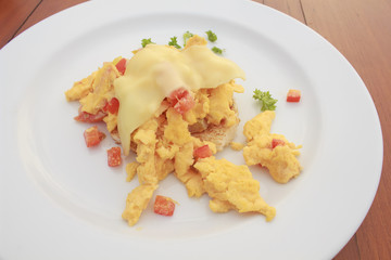 Scrambled egg with cheese and pancake in white dish on wooden table