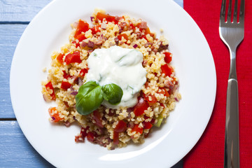 Bulgur salad with tomatoes, onions, bacon and sauce with basil and garlic