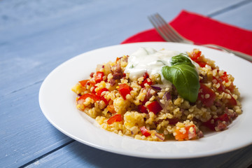 Bulgur salad with tomatoes, onions, bacon and sauce with basil and garlic