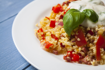 Bulgur salad with tomatoes, onions, bacon and sauce with basil and garlic