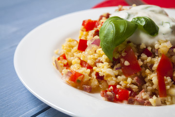 Bulgur salad with tomatoes, onions, bacon and sauce with basil and garlic
