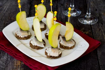 Selbstklebende Fototapeten Appetizer canape with herring, apples on a dark wooden backgroun © elena_hramowa