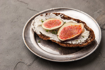 Bread with fresh cheese  , fig and thyme on the vintage metal plate