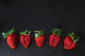 Red strawberries in a row over black