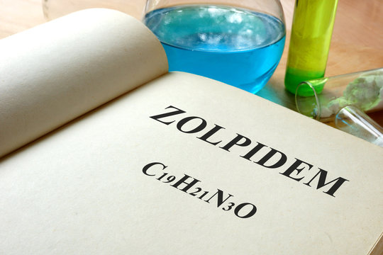 Book with Zolpidem  and test tubes on a table.