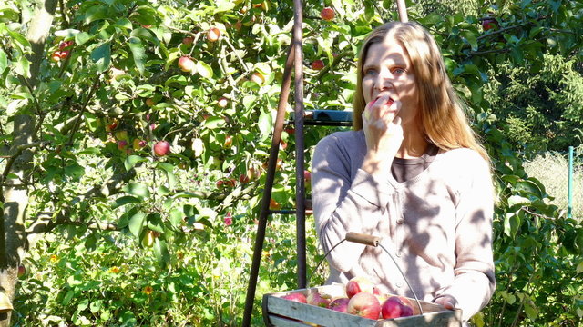 woman sitting on a ladder and eat an apple
