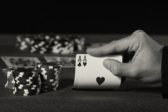 Closeup of poker player with two aces in black and white