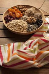 Healthy breakfast. Granola with nuts, seeds, honey, frozen raspberries pumpkin in a wooden biwk on wooden table