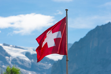 Swiss flag against Alps mountains